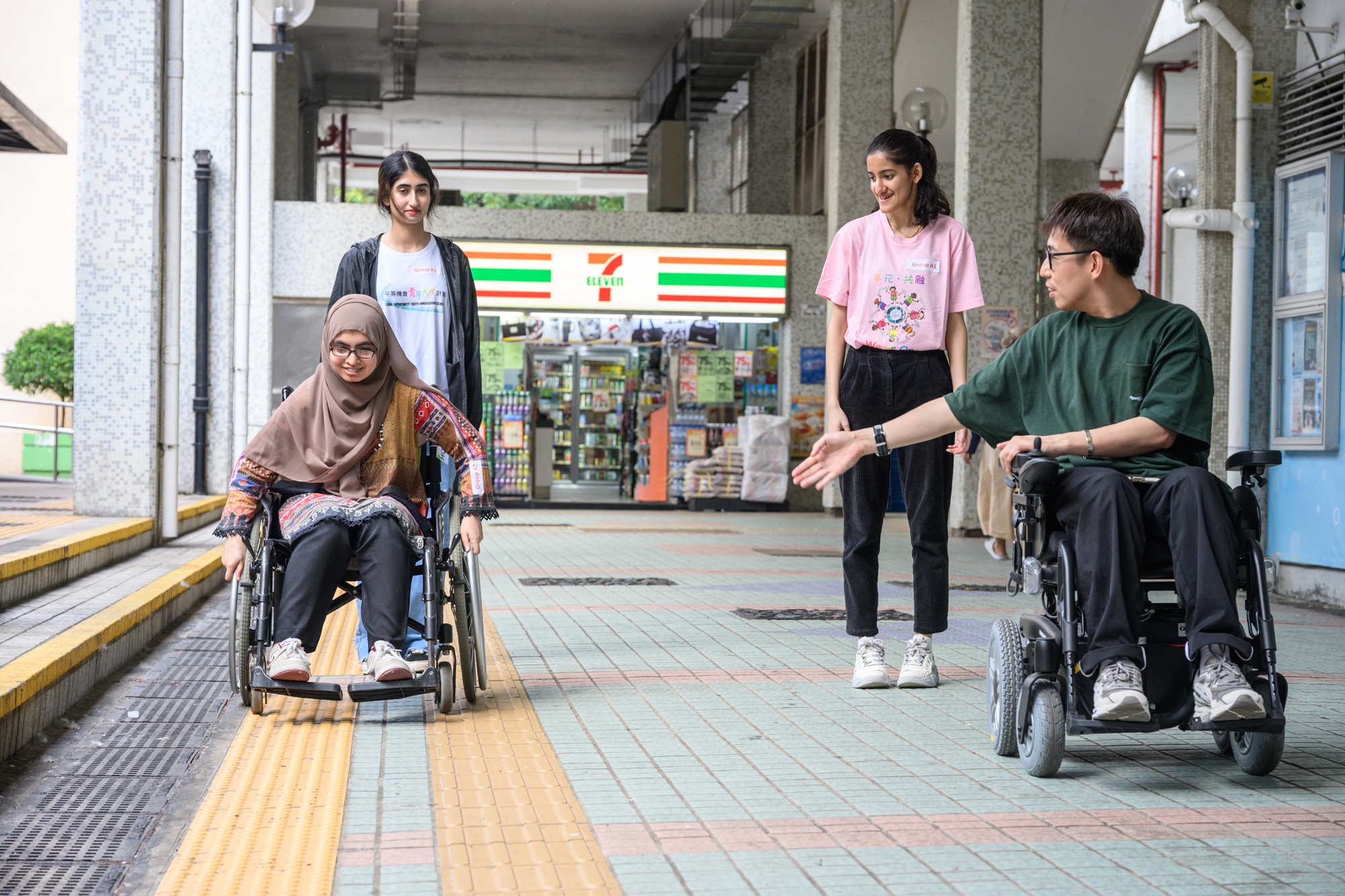 圖示為青年大使乘坐輪椅在社區遊走。